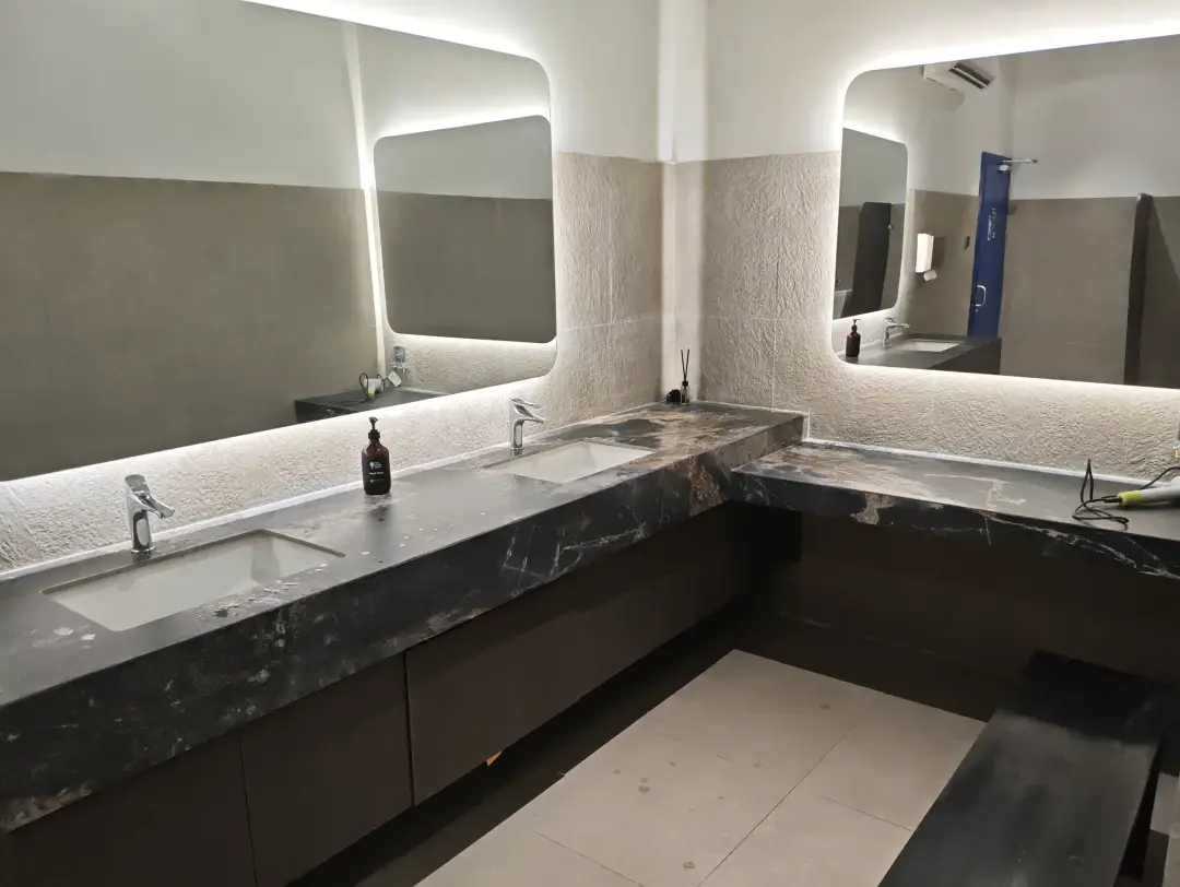 Bathroom with backlit mirrors and marble basins